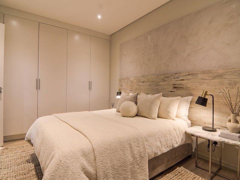Modern bedroom featuring floor-to-ceiling built-in cupboards, a textured feature wall, and warm recessed lighting, creating a clean and contemporary living space.