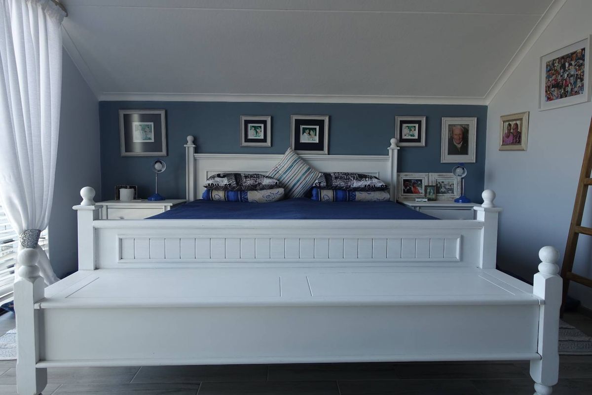 A well-maintained bedroom featuring a vaulted ceiling, tiled flooring, and a blue accent wall.