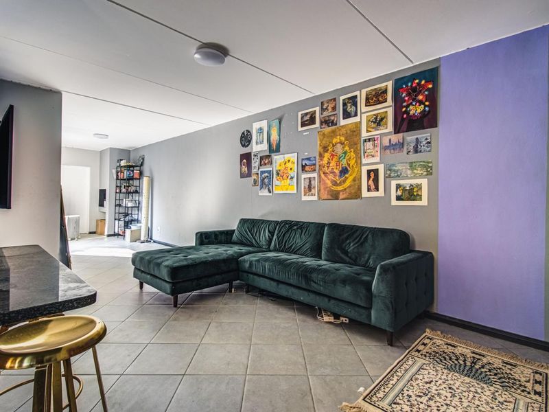 An open-plan living area featuring tiled flooring and a breakfast bar, offering a versatile space for relaxation and dining.