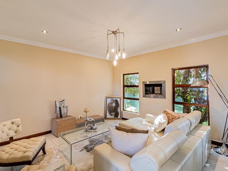 A bright and well-maintained living room featuring a modern recessed fireplace, tiled flooring, and large windows with views of the garden.
