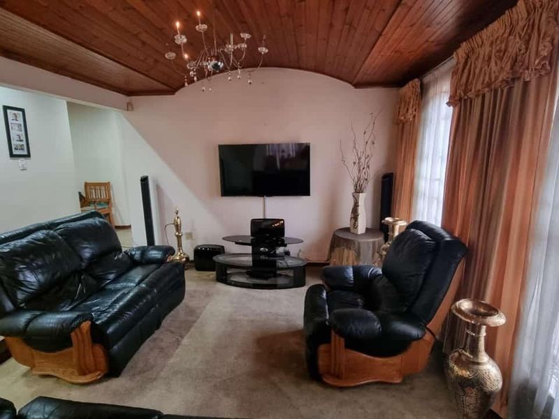 A living room featuring a distinctive timber-clad vaulted ceiling and a central chandelier, providing a traditional aesthetic.