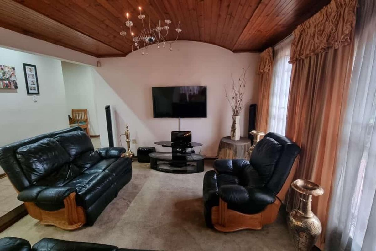 A living room featuring a distinctive timber-clad vaulted ceiling and a central chandelier, providing a traditional aesthetic.