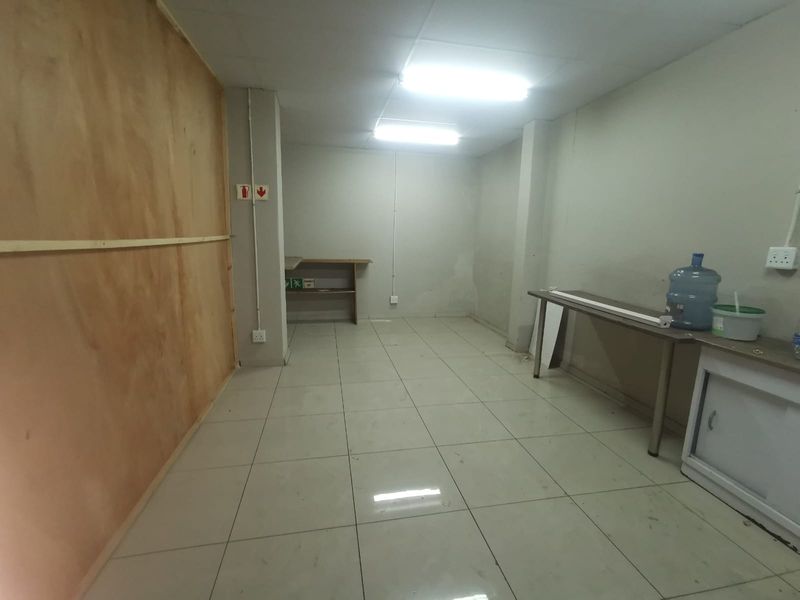 A functional utility or storage space featuring tiled flooring, fluorescent lighting, and basic built-in shelving, suitable for various commercial storage or workspace requirements.