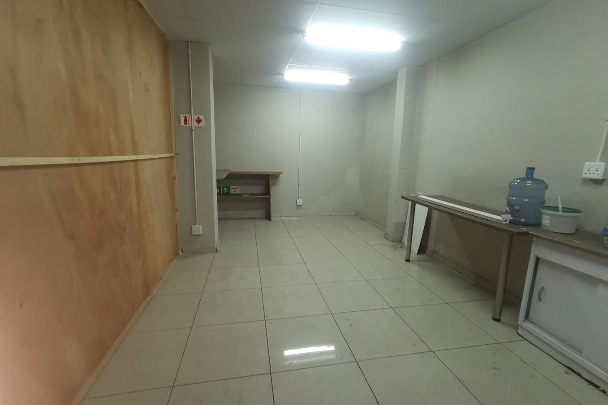 A functional utility or storage space featuring tiled flooring, fluorescent lighting, and basic built-in shelving, suitable for various commercial storage or workspace requirements.