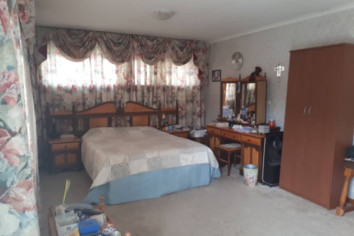 A spacious bedroom featuring neutral carpeting, patterned window treatments, and built-in vanity area, offering a functional layout with ample room for storage.
