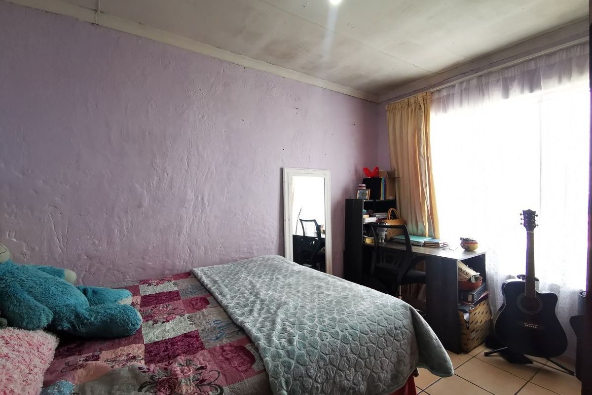 A bedroom featuring tiled flooring and a ceiling light fixture, with visible signs of wear on the walls and ceiling.