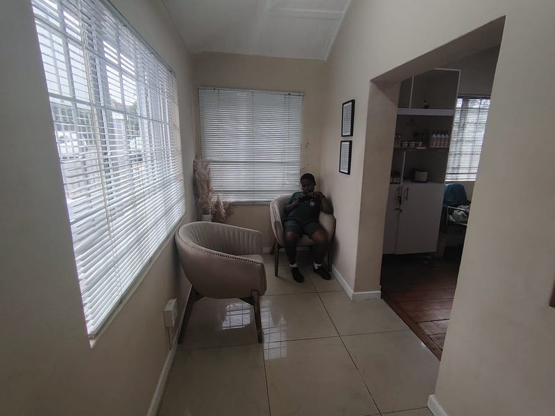 A functional office space featuring tiled flooring, venetian blinds, and built-in shelving, providing a clean and professional environment.