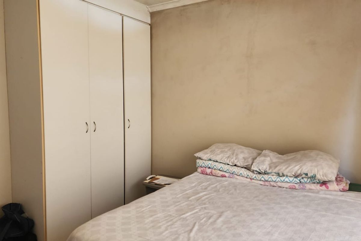 A bedroom featuring built-in cupboards with white doors and plain wall finishes, offering a functional space for rest.