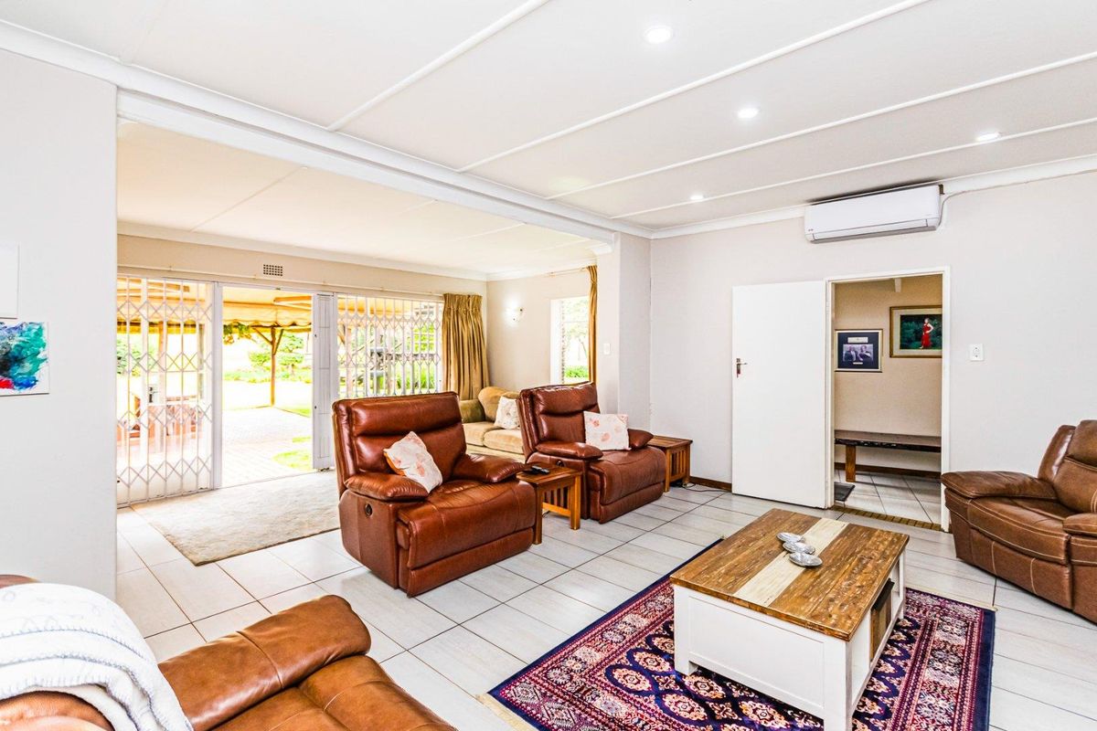 Spacious living area featuring tiled flooring, recessed ceiling lighting, and a wall-mounted air conditioning unit, with direct access to an outdoor patio.