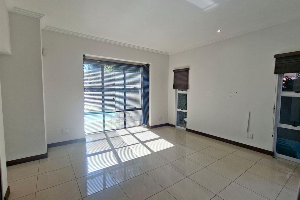 A bright, empty living room featuring large sliding glass doors, tiled flooring, and built-in cabinetry, offering a clean canvas for interior design.
