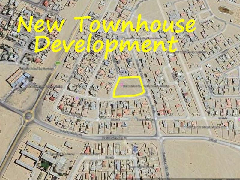 An aerial satellite view highlighting a vacant plot of land designated for a new townhouse development within an established residential area.