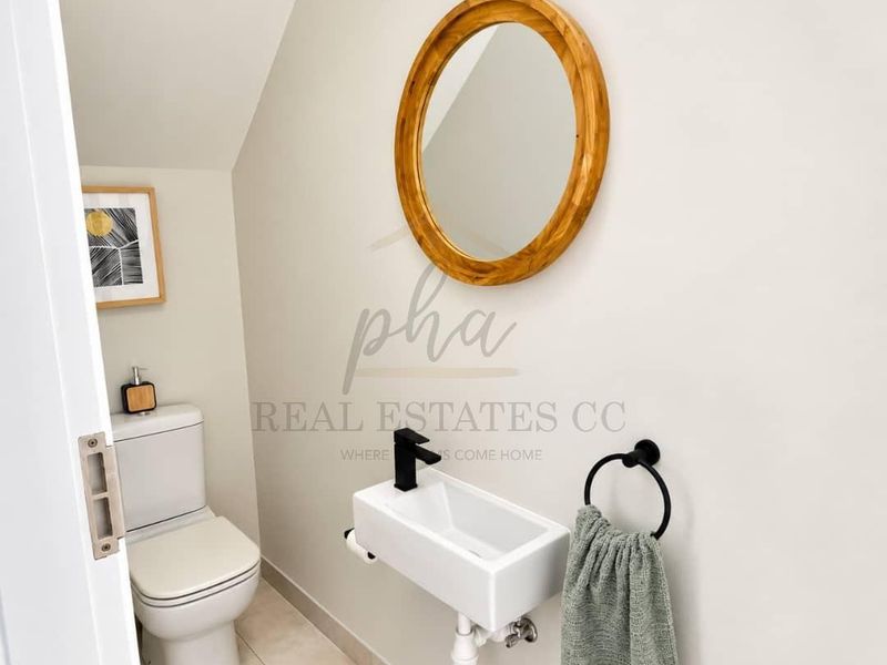 A modern guest cloakroom featuring a wall-mounted basin with a black mixer tap and a standard toilet.