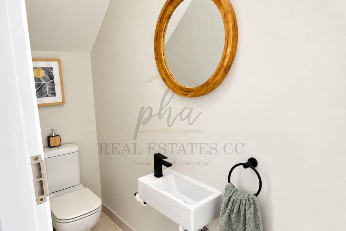 A modern guest cloakroom featuring a wall-mounted basin with a black mixer tap and a standard toilet.