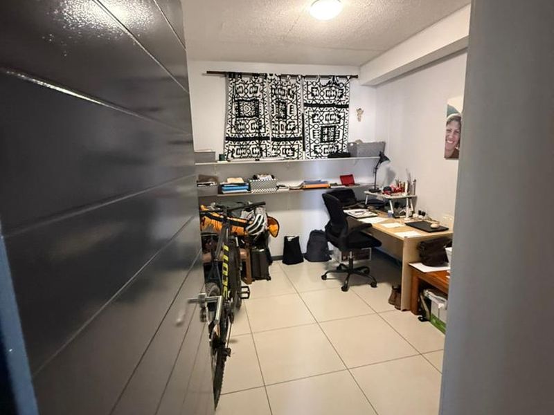 A functional home office space featuring tiled flooring and built-in wall shelving, currently utilized as a workspace.