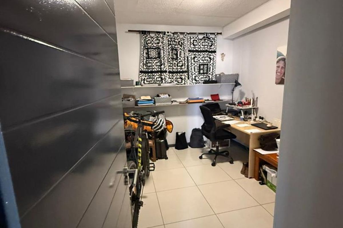 A functional home office space featuring tiled flooring and built-in wall shelving, currently utilized as a workspace.