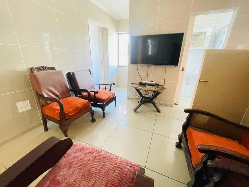 A living area featuring large format floor and wall tiles, providing a neutral base with a wall-mounted television.