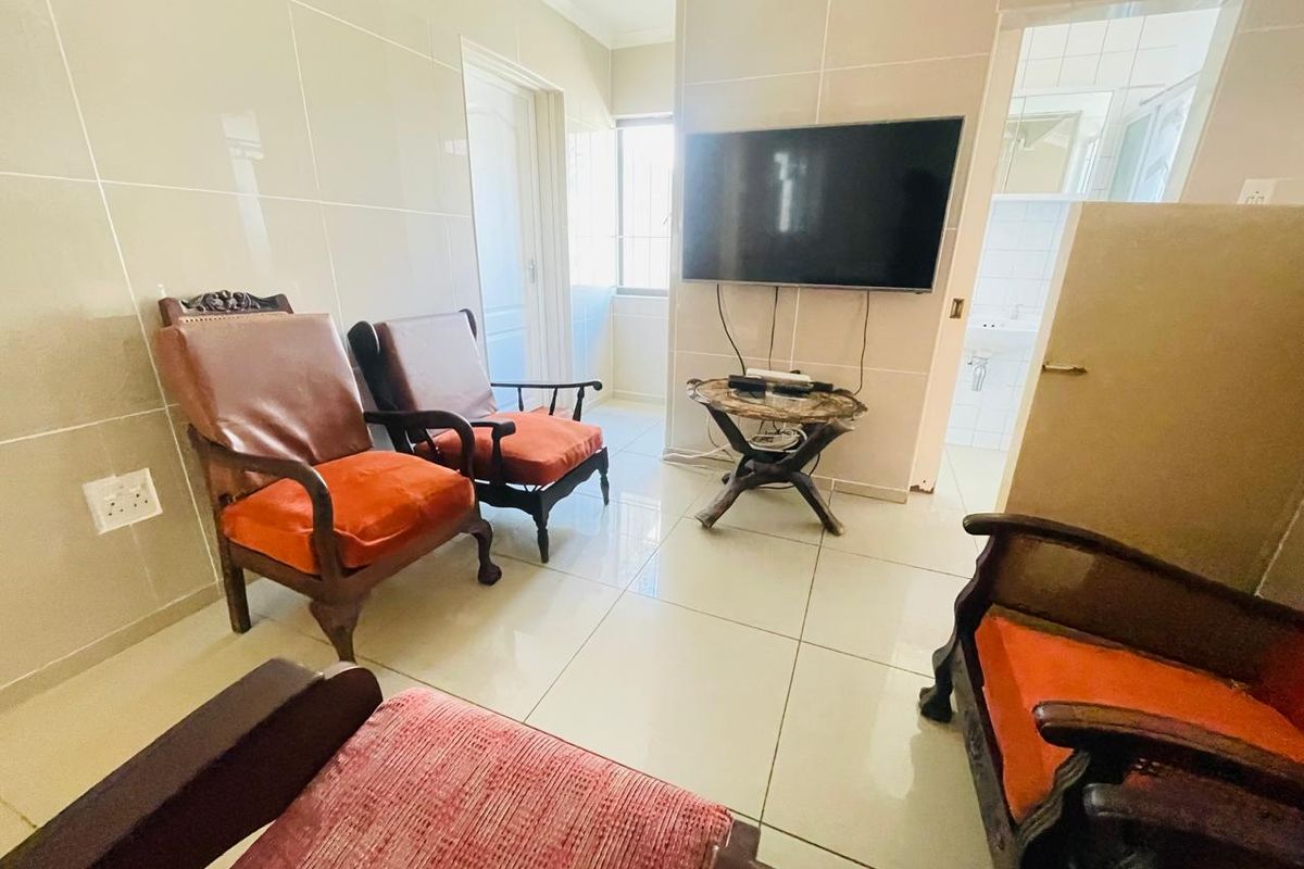 A living area featuring large format floor and wall tiles, providing a neutral base with a wall-mounted television.