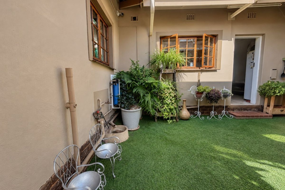 A well-maintained rear courtyard featuring artificial grass, timber-framed windows, and a built-in water filtration system, providing a tidy outdoor space.