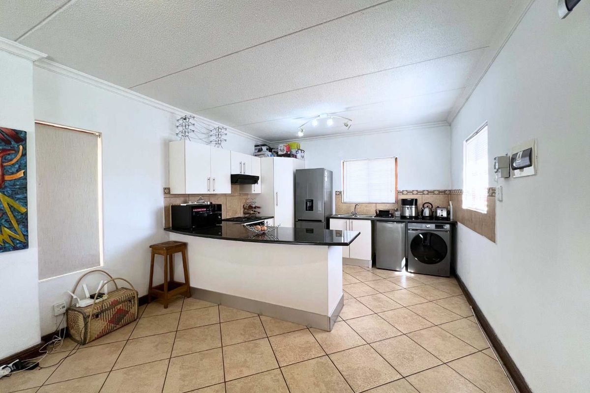 Functional kitchen featuring white cabinetry, dark granite countertops, tiled flooring, and a breakfast bar peninsula.