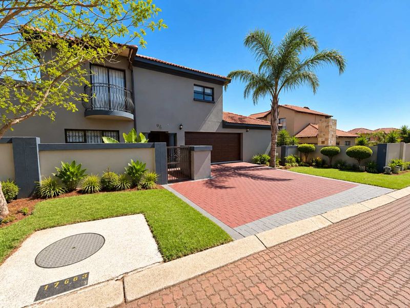 A well-maintained double-story house featuring a paved driveway, double garage, and a balcony, set within a neat residential estate.