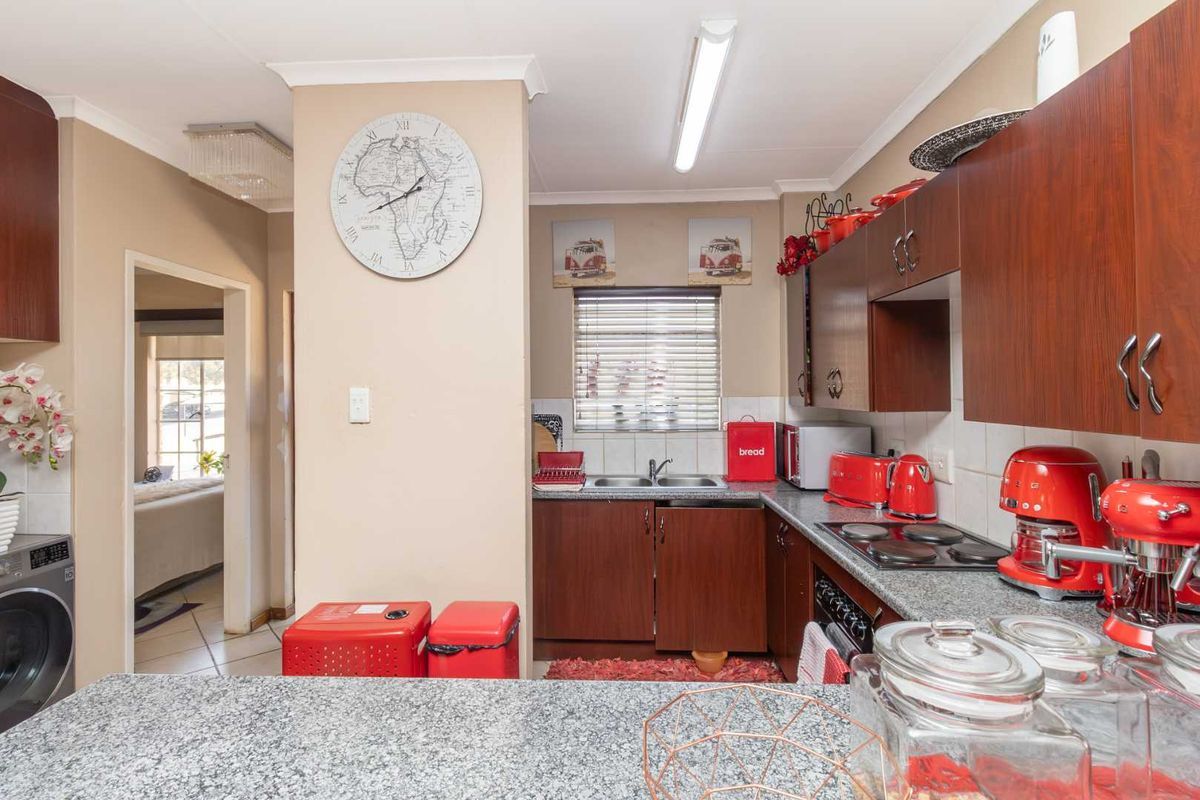 Functional kitchen featuring dark wood-look cabinetry, granite countertops, a double basin sink, and a built-in electric hob and oven.