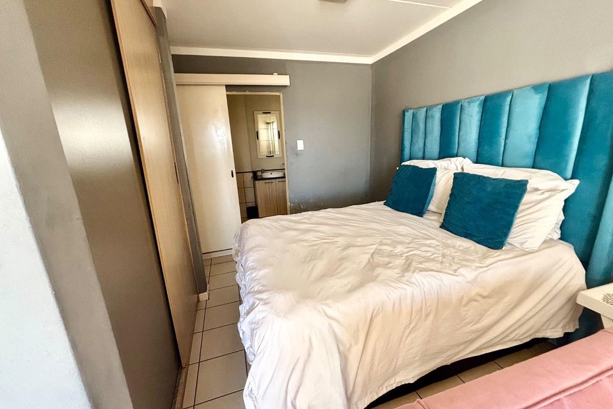 A bedroom featuring tiled flooring, a built-in wardrobe, and direct access to an en-suite bathroom.