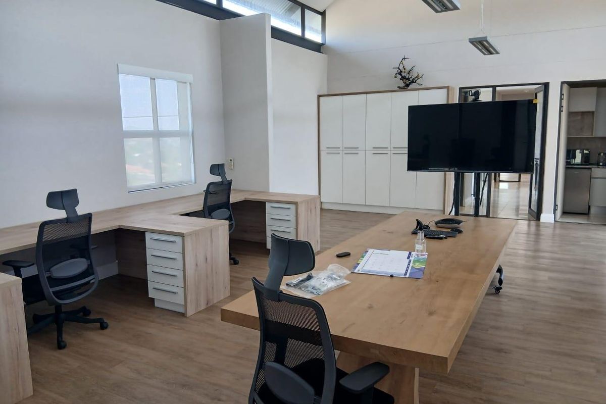 Modern office space featuring vaulted ceilings, clerestory windows for natural light, built-in storage cabinetry, and durable laminate flooring.