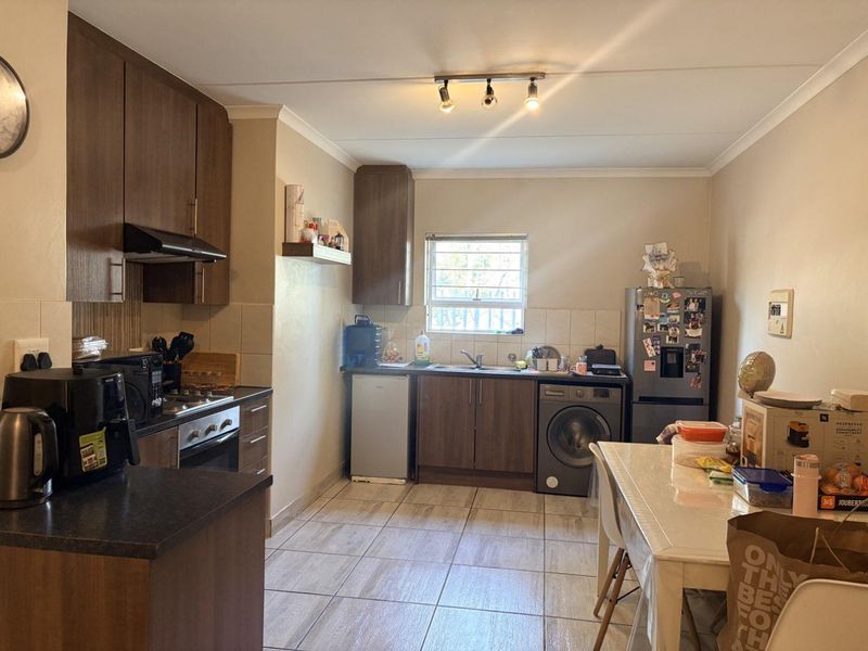 Functional kitchen featuring dark wood cabinetry, tiled flooring, built-in oven with extractor fan, and integrated plumbing for laundry appliances.
