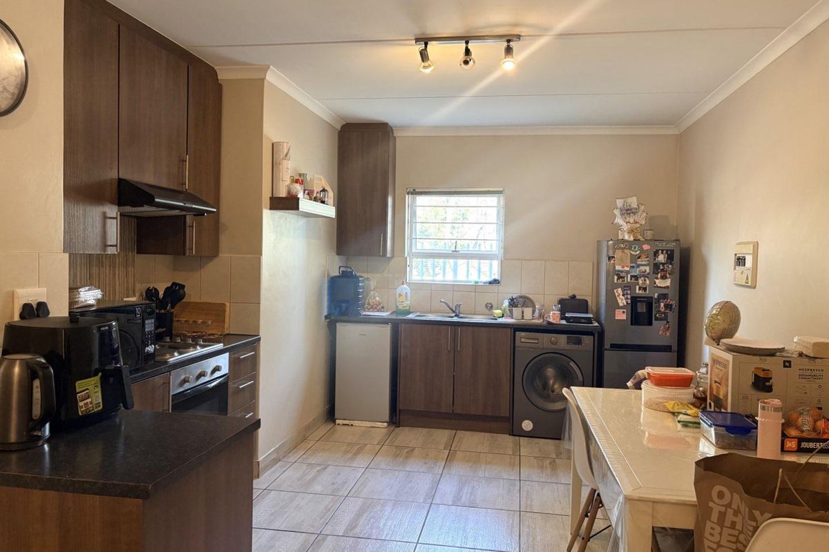 Functional kitchen featuring dark wood cabinetry, tiled flooring, built-in oven with extractor fan, and integrated plumbing for laundry appliances.