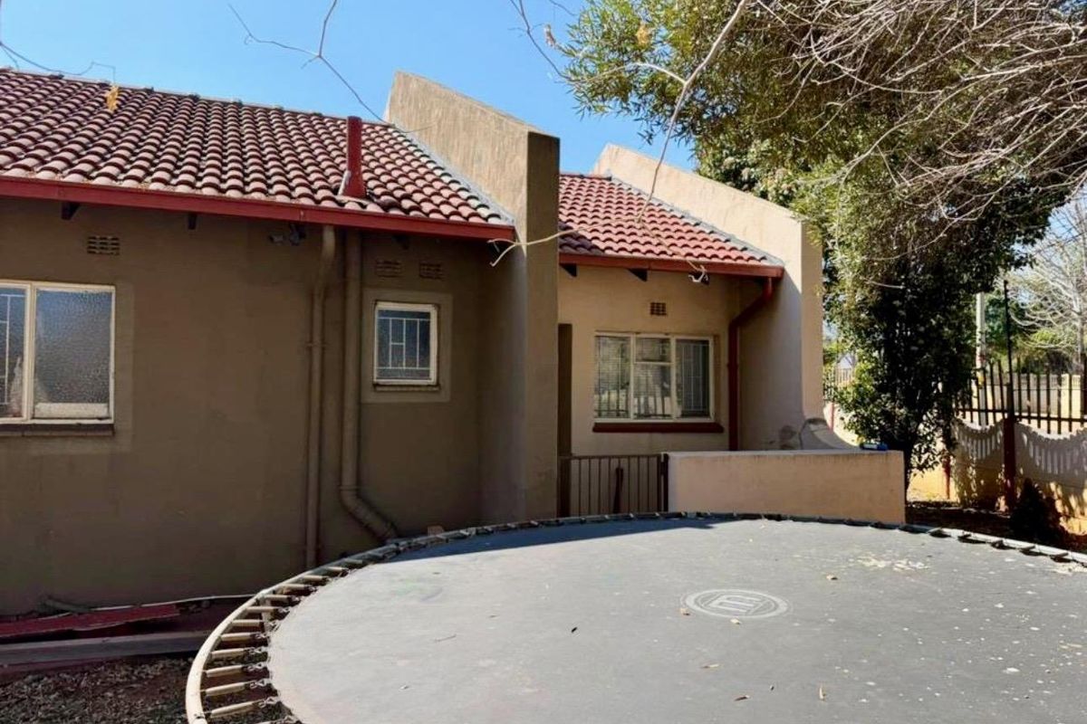 Rear view of the property showing the plastered exterior walls, tiled roof, and security-fitted windows.