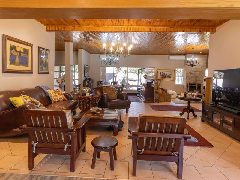 Spacious open-plan living area featuring a timber-clad ceiling, ceramic floor tiles, and a stone-clad fireplace, creating a warm and inviting atmosphere.