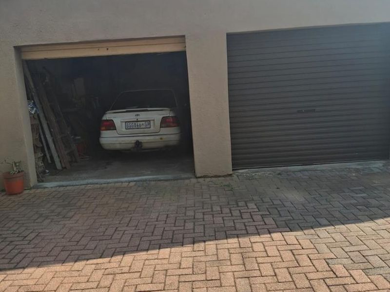 A double garage with a paved driveway, featuring one open bay and one closed roller shutter door.