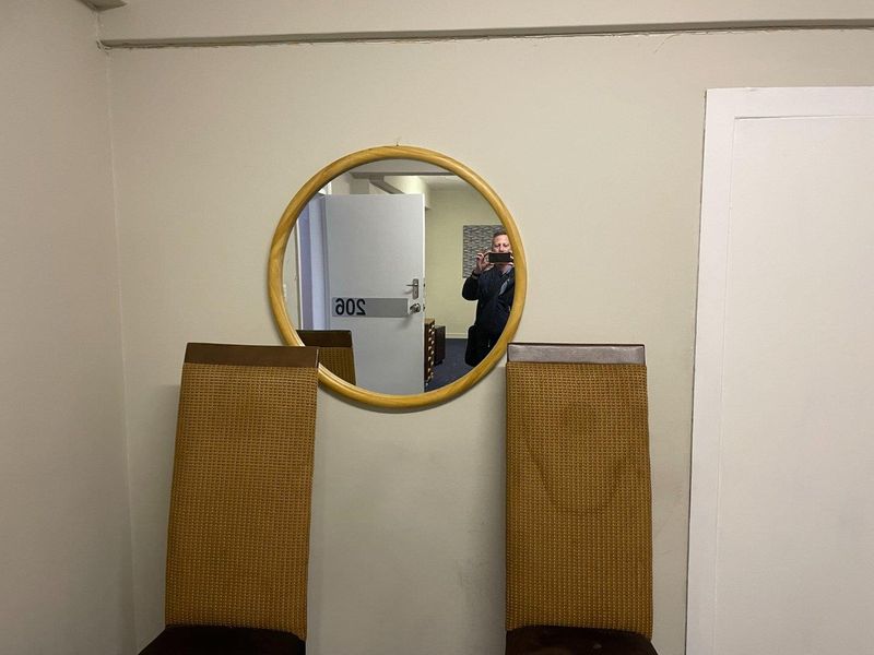 A view of an office interior featuring a wall-mounted circular mirror and doorway.