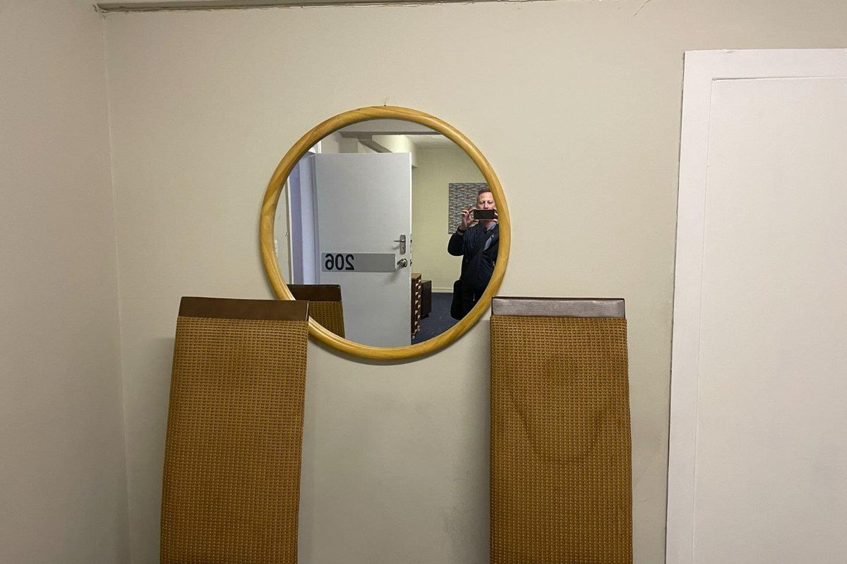 A view of an office interior featuring a wall-mounted circular mirror and doorway.