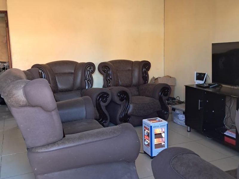 A living room featuring tiled flooring and plain walls, currently showing signs of wear and requiring cosmetic updates to improve its overall condition.