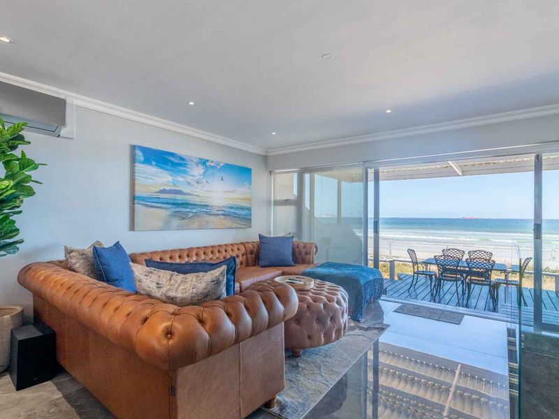 Spacious open-plan living area featuring large sliding glass doors that open onto a balcony with direct ocean views.