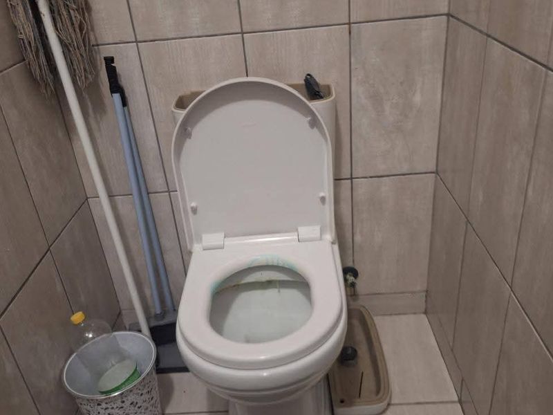A small bathroom featuring tiled walls and flooring with a standard toilet. The space requires maintenance and cleaning to improve its condition.