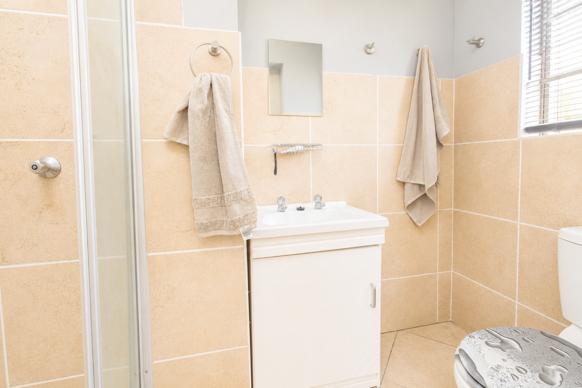 A functional bathroom featuring a vanity basin, a shower enclosure with a glass door, and tiled walls.