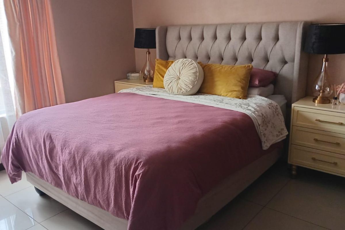A well-maintained bedroom featuring neutral wall tones and tiled flooring, providing a comfortable and functional sleeping space.