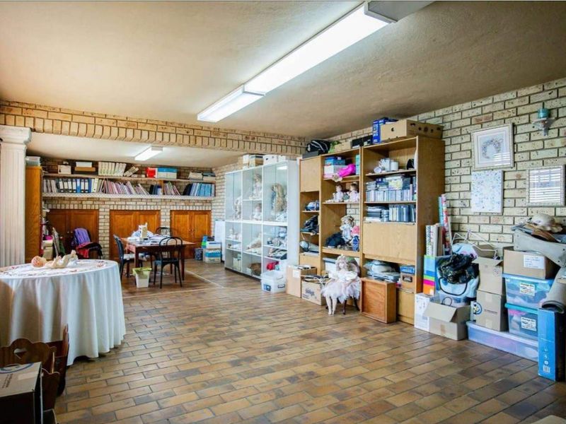 Spacious living area featuring exposed brick walls, durable tiled flooring, and built-in wooden cabinetry, offering a versatile space for various uses.