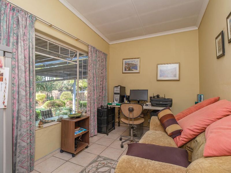 A functional office space featuring tiled flooring and a large window providing natural light and views of the garden.
