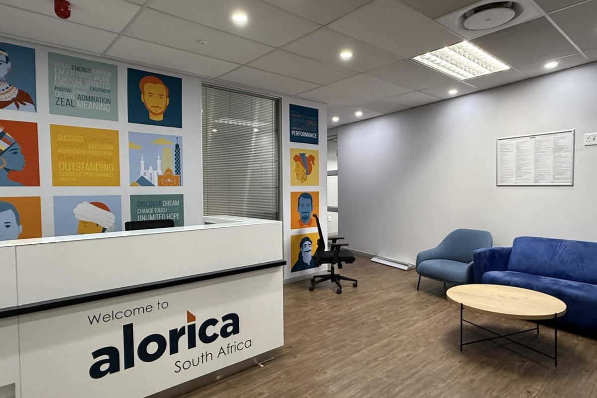 Modern office reception area featuring a branded reception desk, suspended ceiling with recessed lighting, and durable laminate flooring.