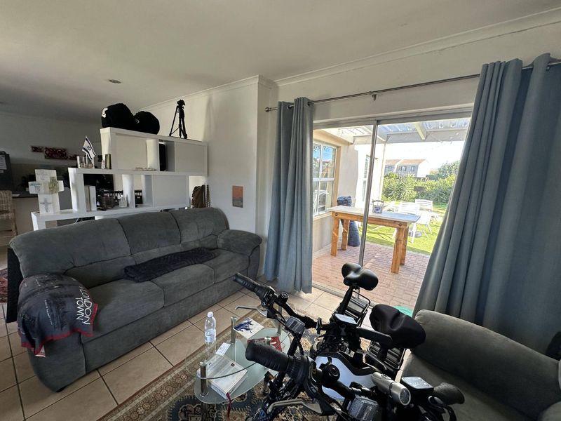 Open plan living area featuring tiled floors and large sliding glass doors providing direct access to a covered patio and garden space.