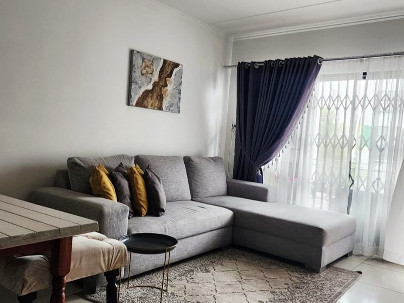 A bright living room featuring tiled flooring, a sliding glass door with security gate, and neutral wall finishes.