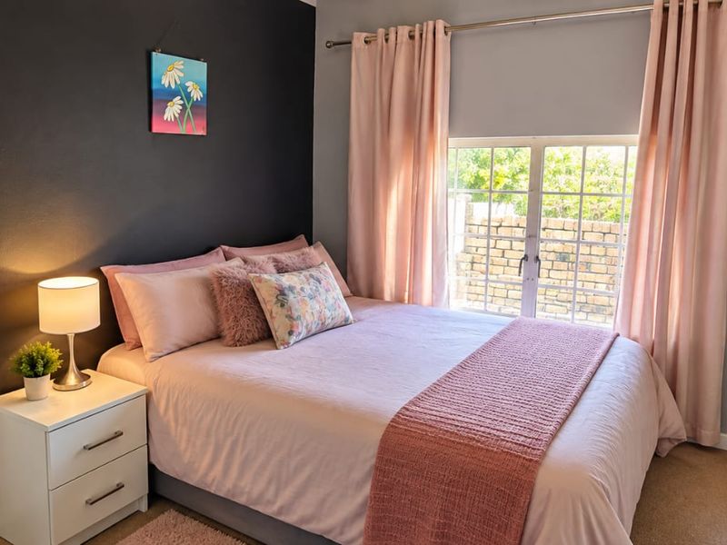 A cozy bedroom featuring a built-in wardrobe, carpeted flooring, and a window with security bars, finished with a modern accent wall.