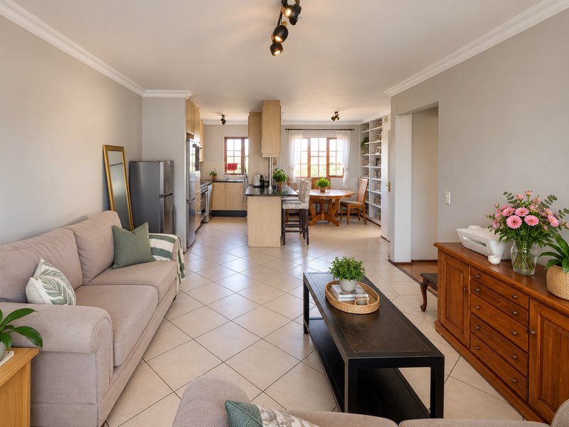 Spacious open-plan living and kitchen area featuring tiled flooring, modern cabinetry, a central kitchen island, and built-in shelving units.