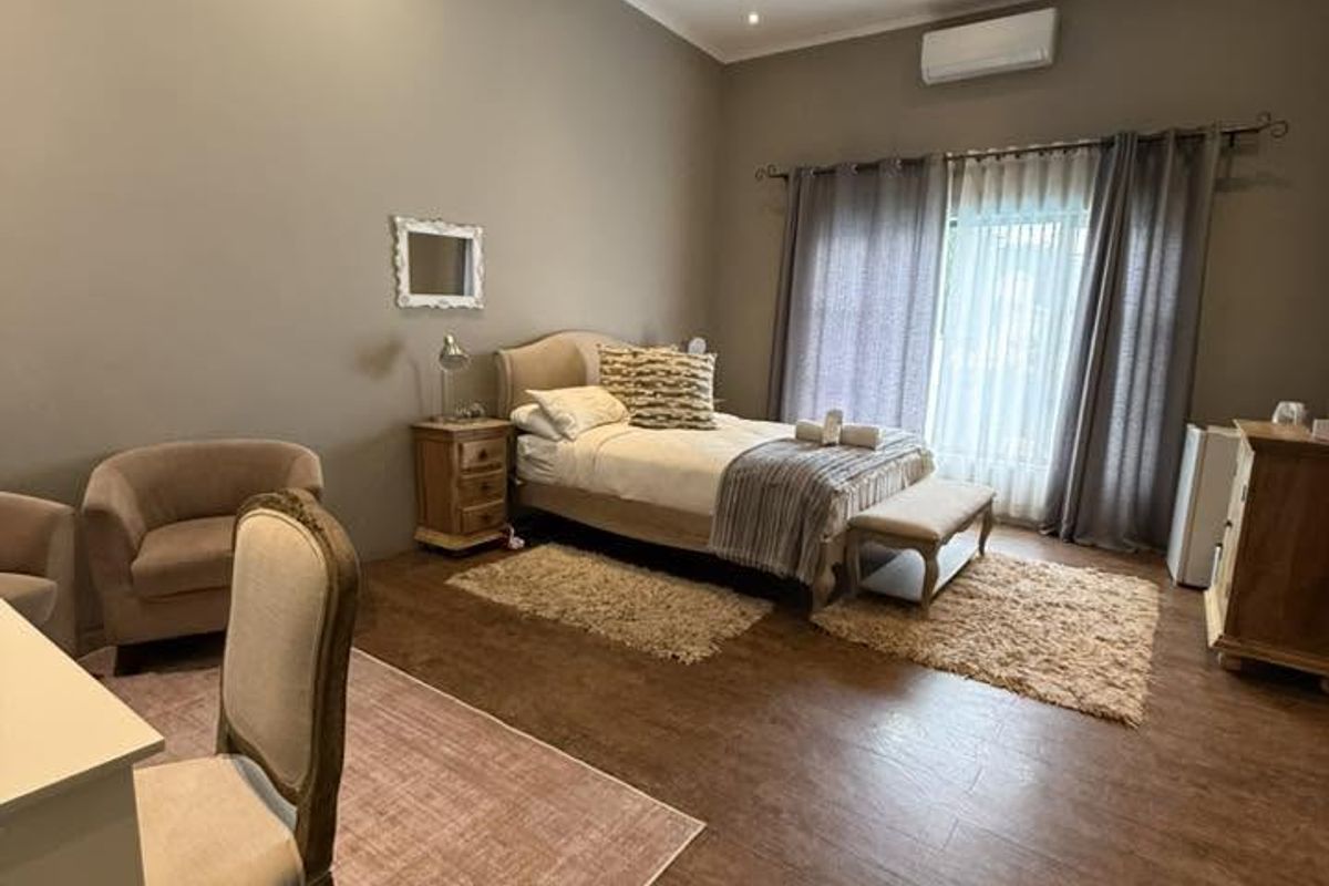 Spacious bedroom featuring wood-look tile flooring, recessed lighting, a ceiling fan, and a wall-mounted air conditioning unit with direct access to a patio.