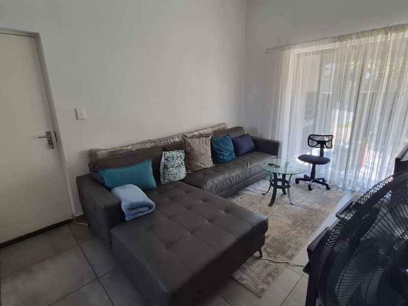 A living room area featuring tiled flooring and a large sliding glass door providing access to the outdoor space.