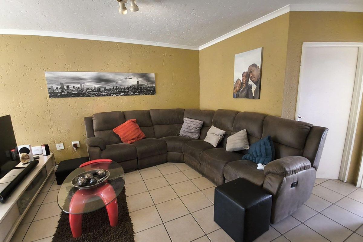 A living room featuring tiled flooring, textured walls, and a ceiling-mounted light fixture.