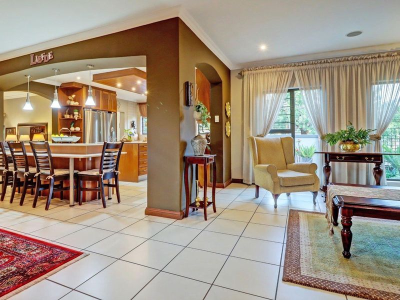 Spacious open-plan living area featuring a kitchen with a central island, tiled flooring, and seamless flow to the adjacent lounge with garden access.